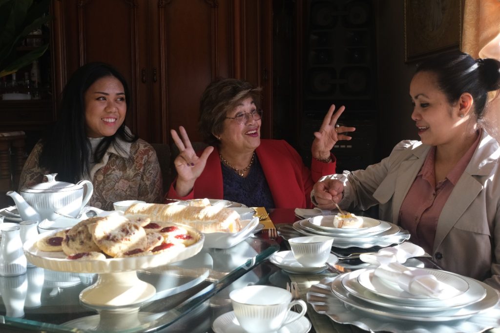 The Gillies family eating cakes and drinking tea in their dining room